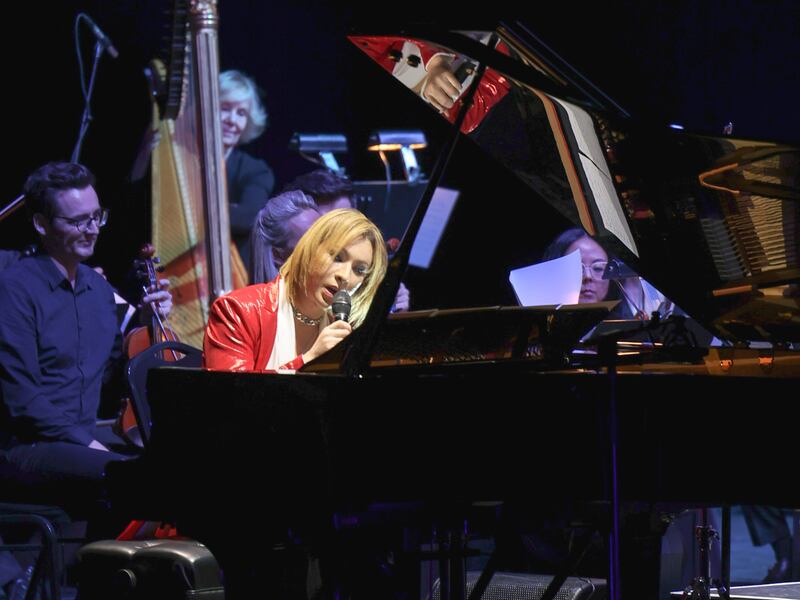 Photo of a man holding a microphone at a piano