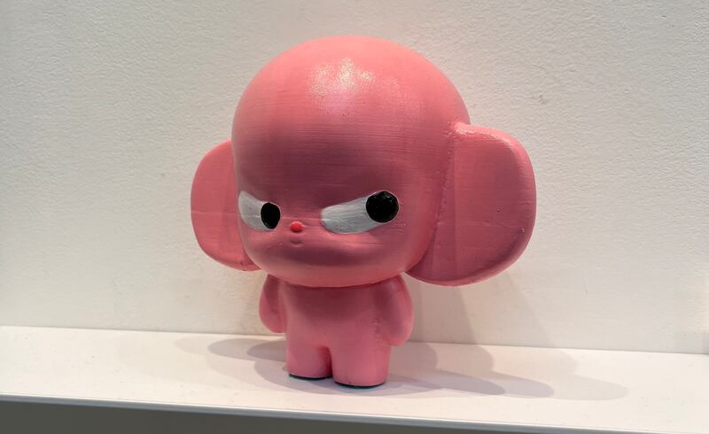 Photo of a pink statue of a humanoid figure with a large head, cartoonish eyes, and massive ears