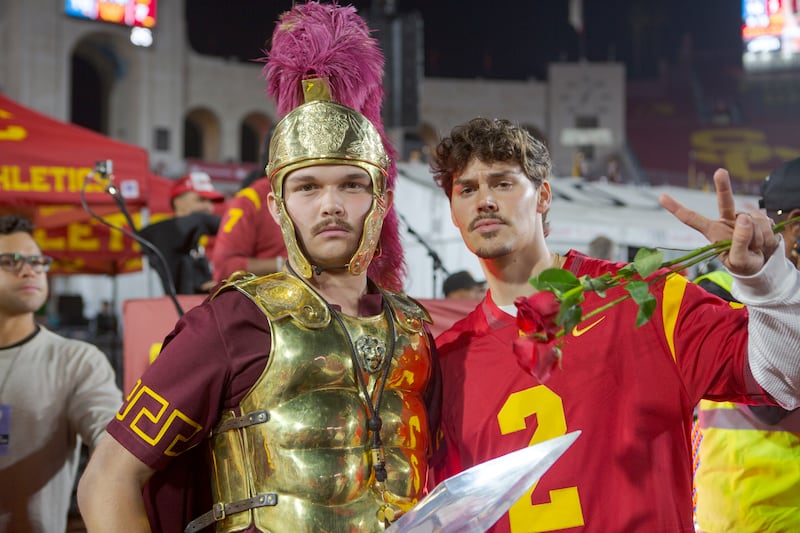 Noah holds up a fight on sign while posing seriously with the drum major.