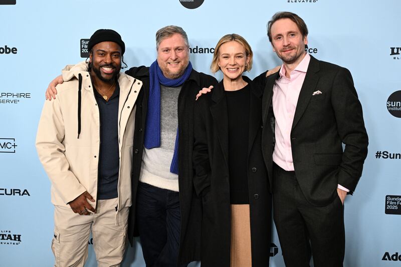 Ndifornyen wears a tan pants and jacket, with a dark shirt on under and a black beanie. Ket wears black pants a jacket, a gray sweater and a blue scarf. Mulligan has a black sweater and jacket, with a tan bottom. Basden has on a black suit jacket and pant, with a pink undershirt.