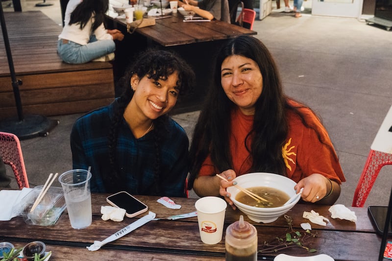 Two people sit side by side at a table with soup