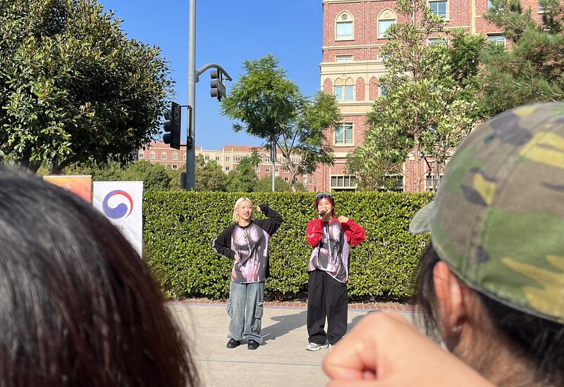 Photo of two people in front of a bush dancing