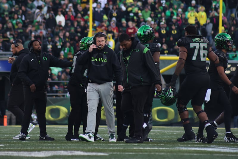 Dan Lanning paces the Oregon sideline. Other coaches/players and the Autzen Stadium crowd can be seen in the background.