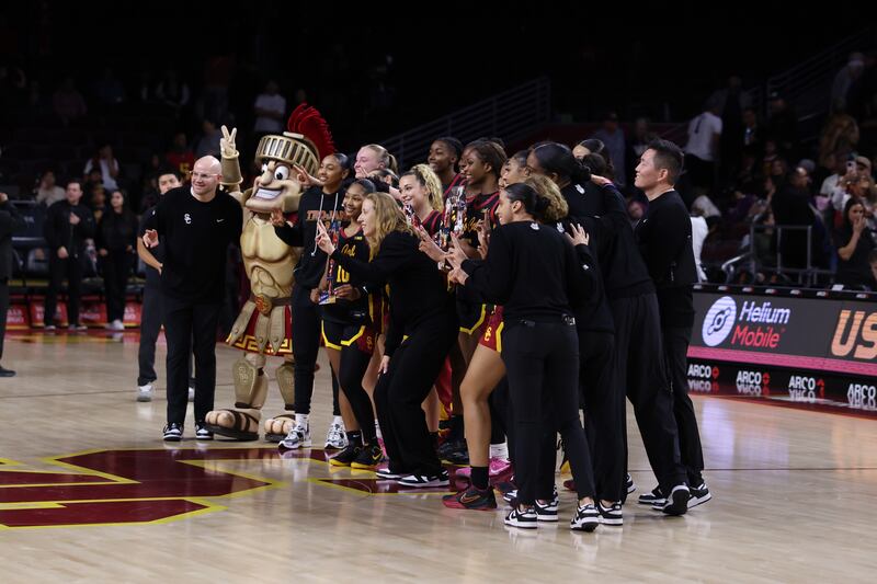 USC women's basketball team and coaches pose for a photo with Tommy Trojan at midcourt at Galen Center.