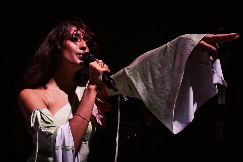 Photo of a woman in green with a microphone pointing