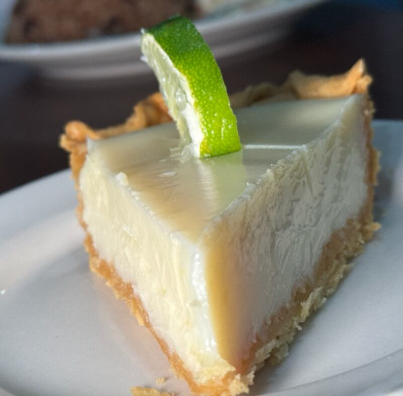 Photo of a slice of lemon pie with a lime wedge in it.
