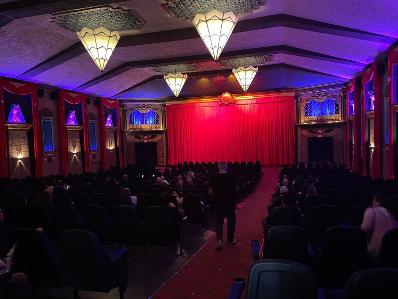 Photo of a dark auditorium with a large red curtain at the front