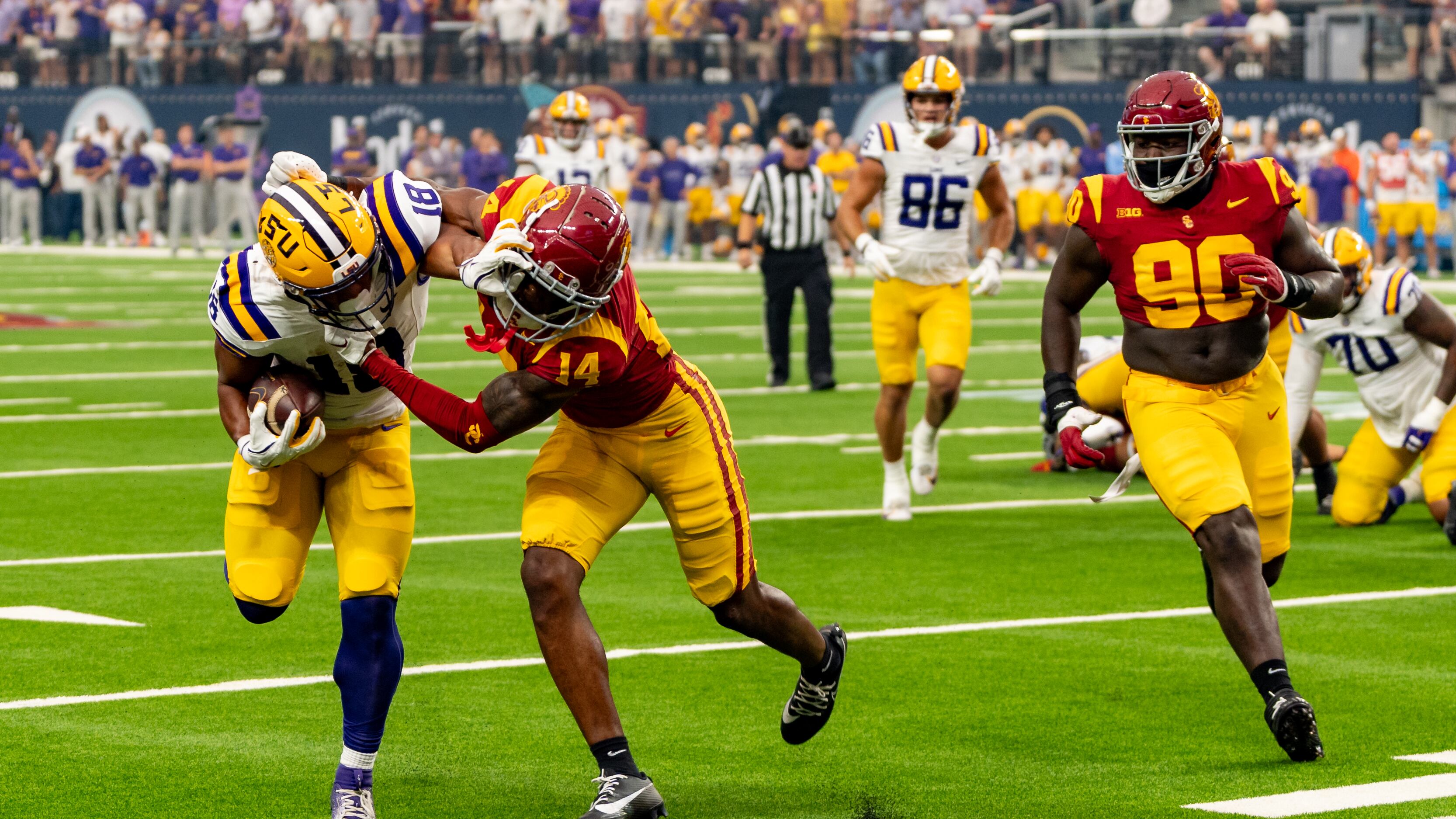 A photo of an LSU offensive player attempting a stiff arm on a USC defender.