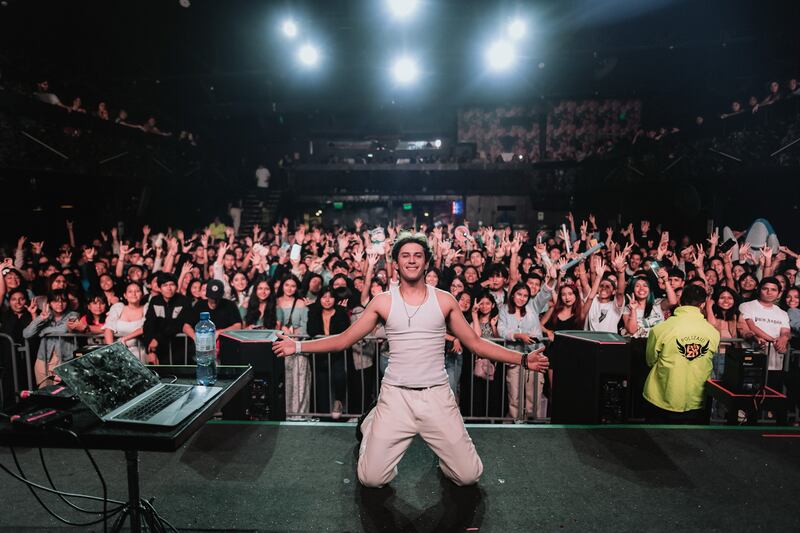 Photo of a musician posing with many fans behind him.