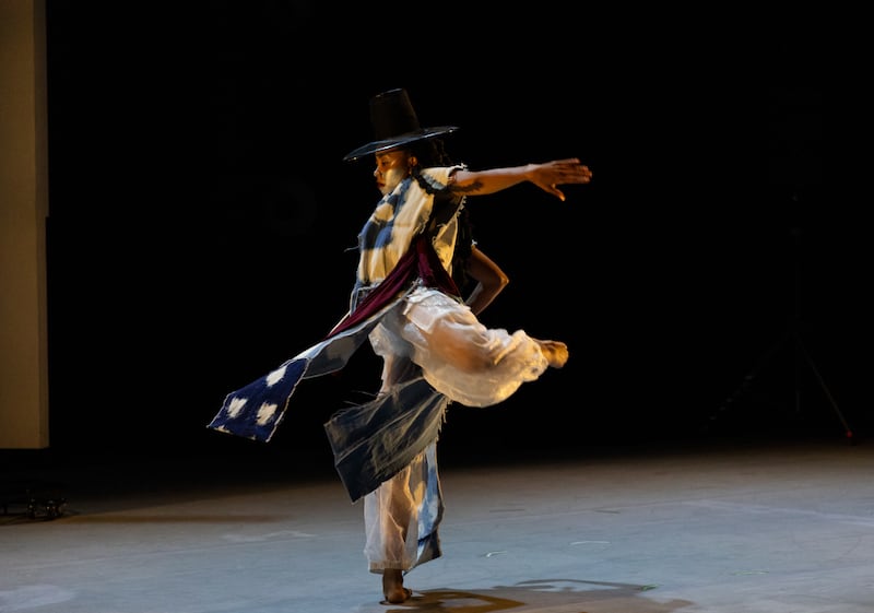 Dancer in a black hat dressed in long denim shall.