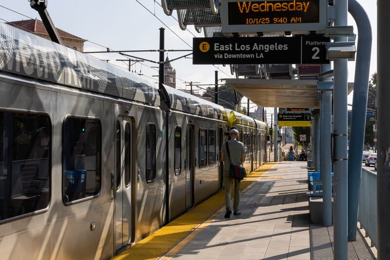 A man walks down the train station platform next to the Metro E Line.