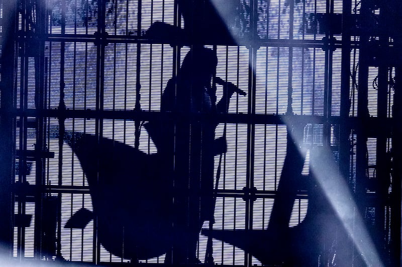 Photo of a silhouette of a woman behind cage-like bars