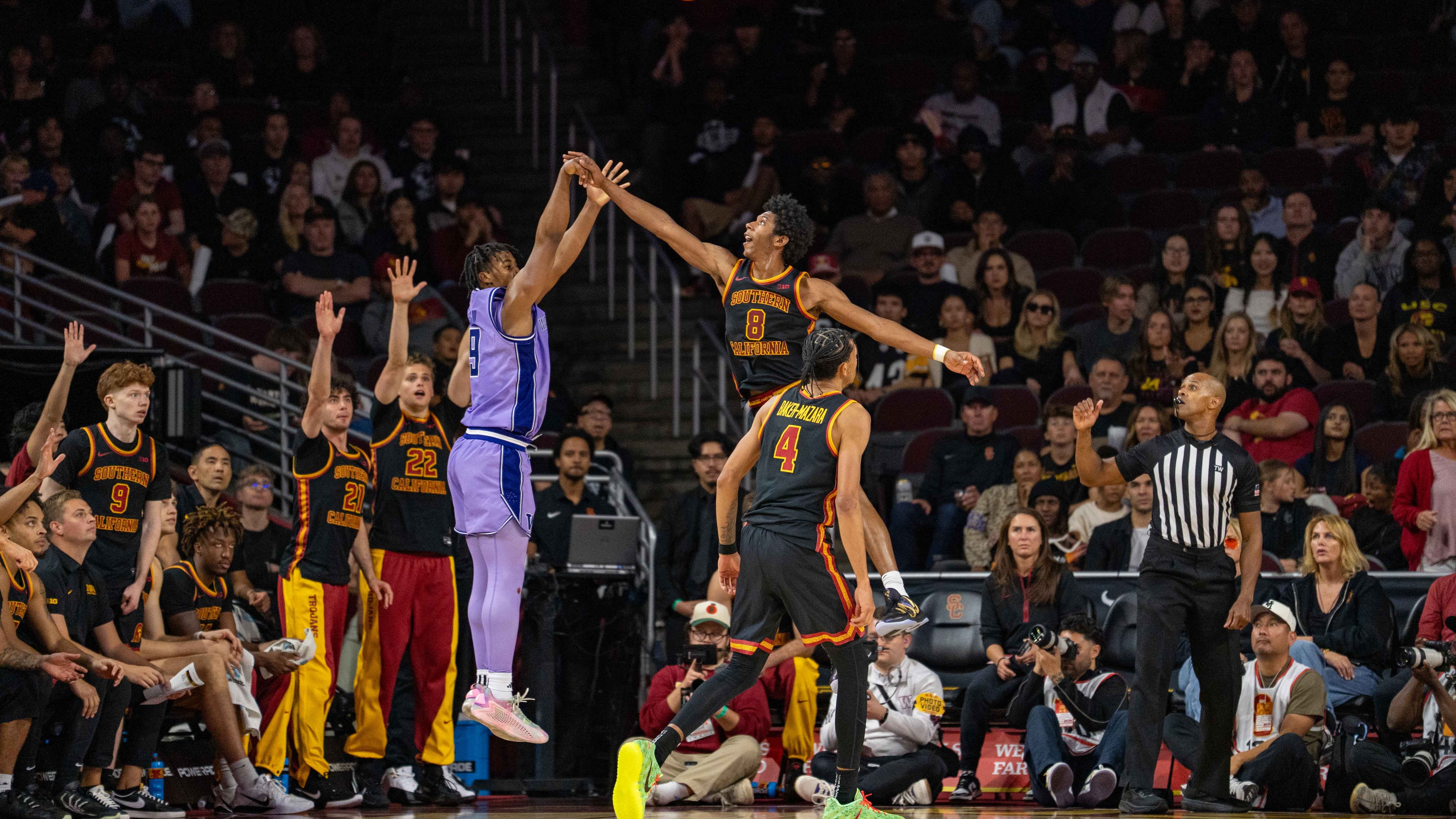 Player in a black uniform blocks shot against the player in a purple uniform.