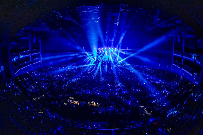 Photo of a crowd of people and a stage that is glowing blue with spotlights