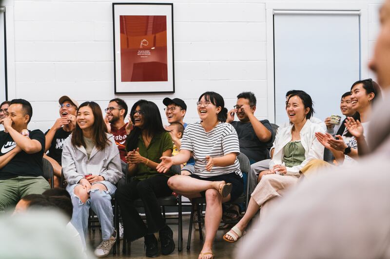 Two rows of people sitting smile, clap and laugh.