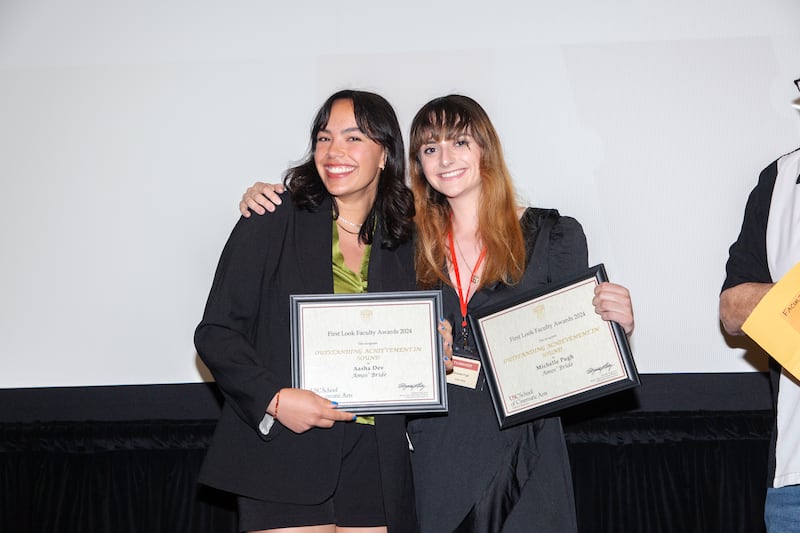 A photo of two students holding up their certificates for their award and posing.