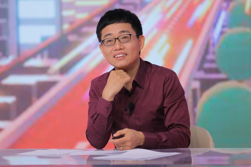 Photo of a man sitting at a desk in front of a colorful background