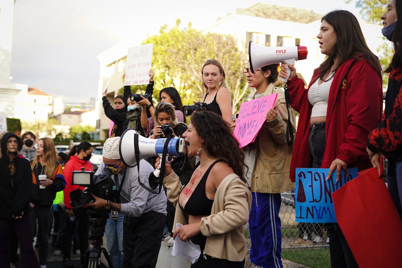 Protestors chanting with megaphones during a march against sexual assualt.