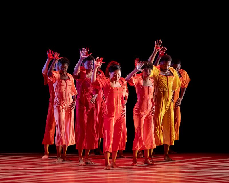 Alvin Ailey American Dance Theater groove together in a group with one hand up in praise in "Love Stories."