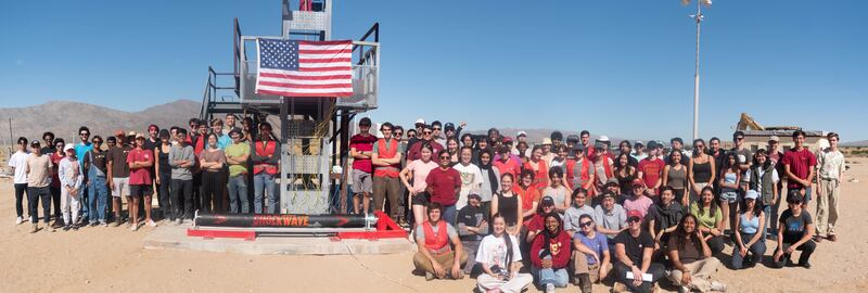 RPL students stand and sit next to the integrated motor before the static fire. The building and completion was a team effort and contributions all around got the motor to the stage it was at.