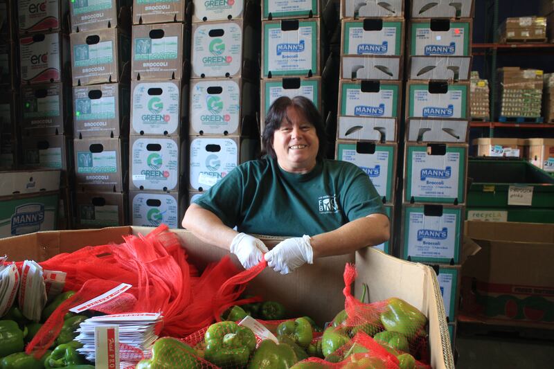 A photo of a woman packing bell peppers at a food bank.