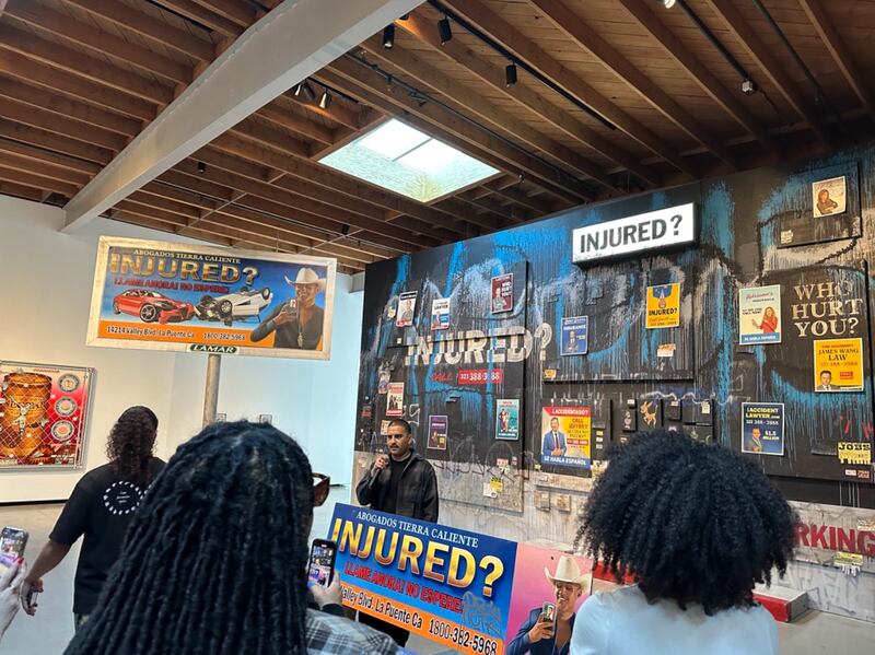 A black and blue gallery wall is filled with different signs reading "Injured?" and photos of lawyer faces.