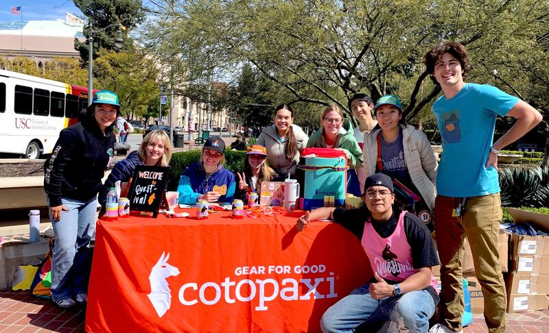 A photo of students at a table with the Cotopaxi logo on it.