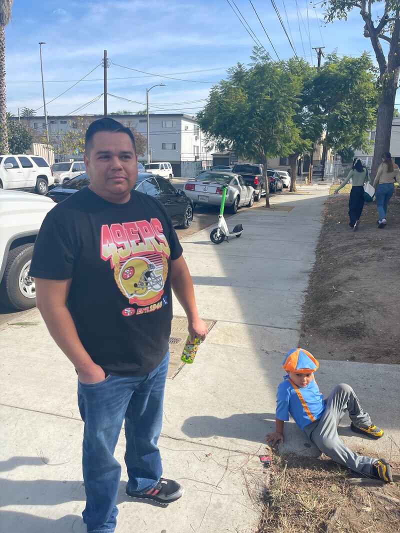 A photo of a man and a little boy on a sidewalk.