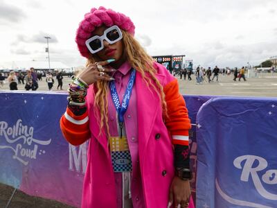 A photo of a fan wearing a bright punk and orange outfit with accessories like sunglasses and a hat.