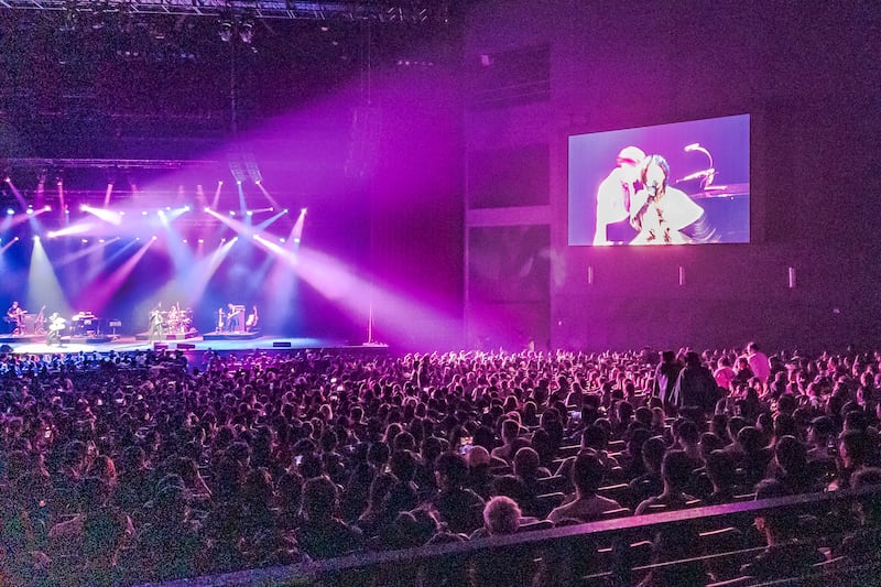 A packed theater watches the performance on stage.