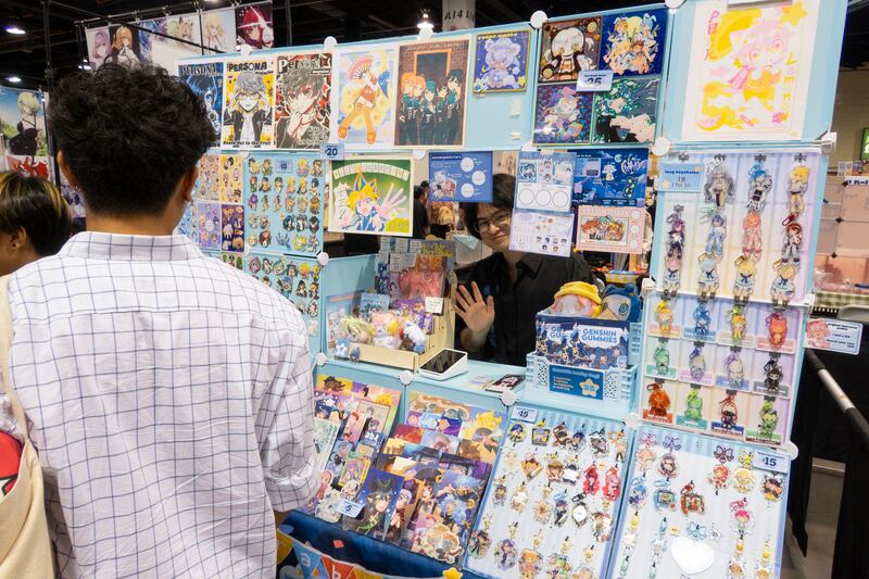 Artist waves at the camera while selling merch