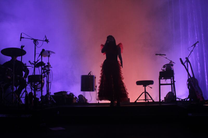 Photo of a woman's silhouette standing on a red and purple stage