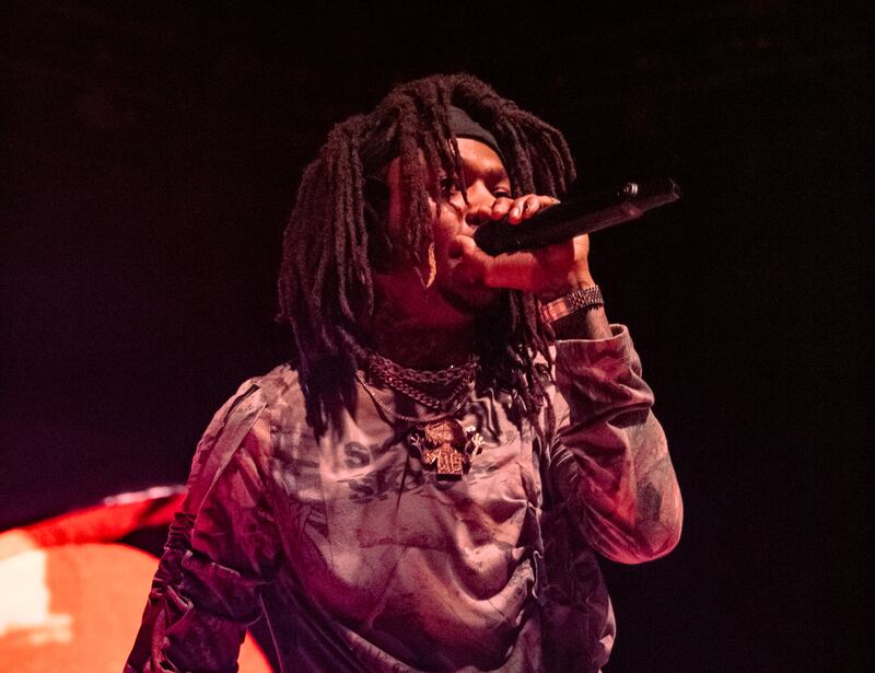 A photo of J.I.D singing into the microphone during his set on stage.