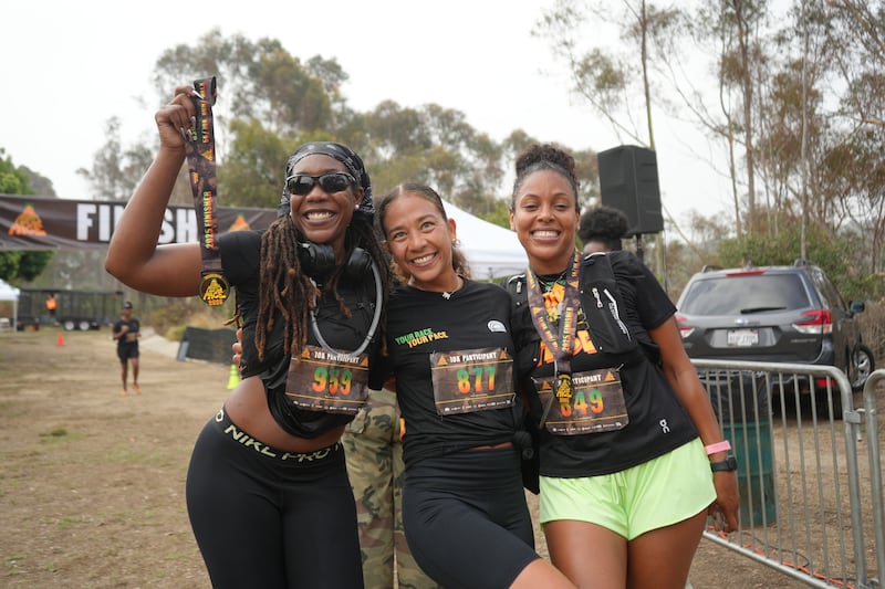 Three friends celebrate together after crossing the finish line at WalkGood LA’s People’s Pace 10K in Los Angeles on Sept. 21, 2025.