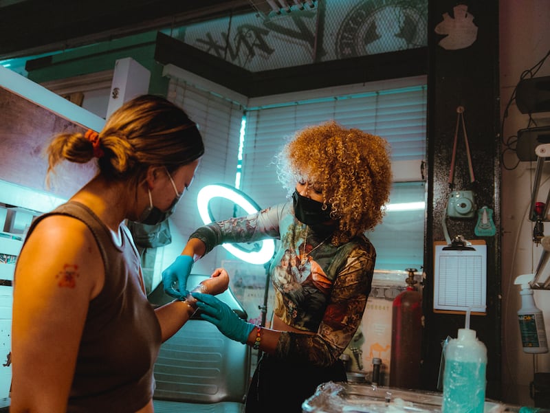 Bryant wraps Ye’s tattoo with a layer of petroleum jelly and bandage. (Photo by Alex Lam)