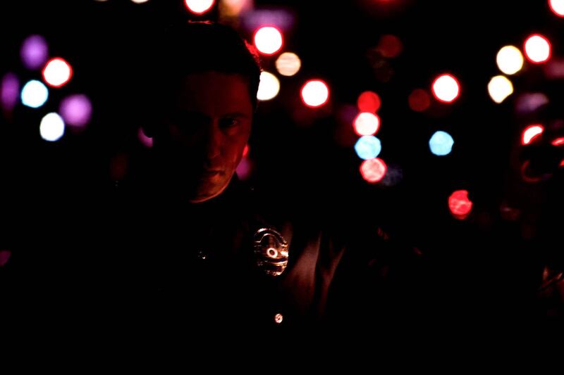 [Photo of LAPD officer lit by red patrol car light.]