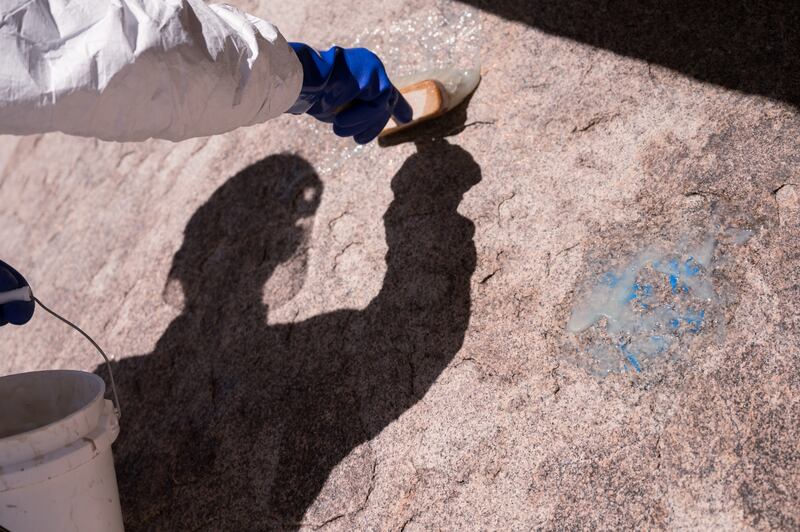 John-Thomas “JT” Faust, a volunteer climbing steward with Friends of Joshua Tree, applies “Elephant Snot,” a caustic chemical designed to remove paint, onto the graffiti. (Photo by Michael Chow)