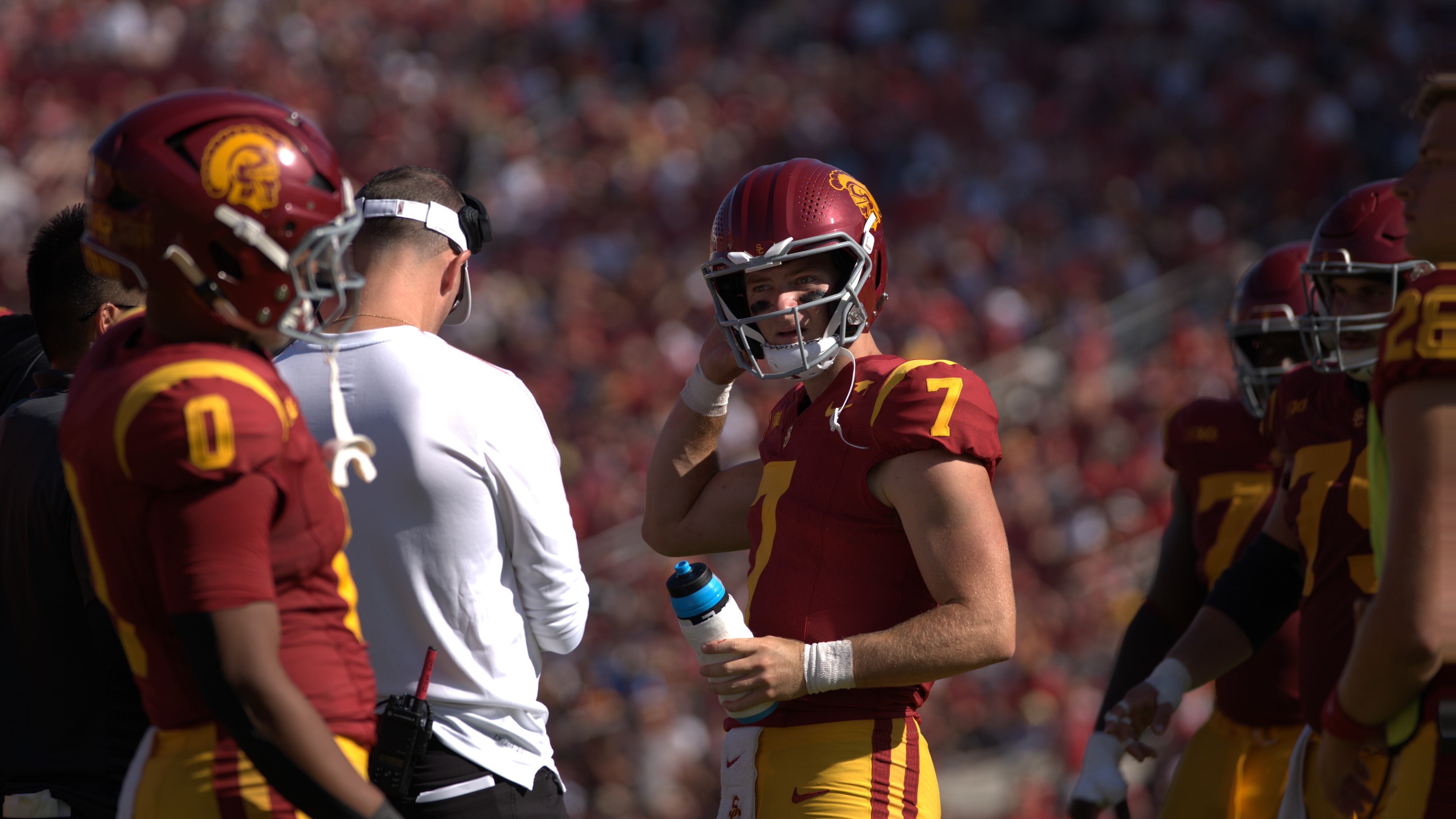 A photo of Miller Moss, in full red uniform, holding a water bottle next to Lincoln Riley.