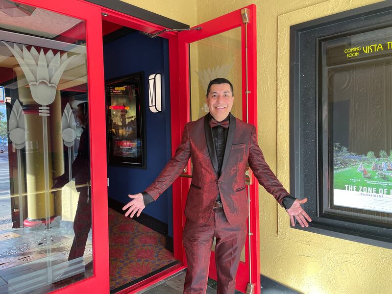 Photo of a man in a red tuxedo standing in front of an open door