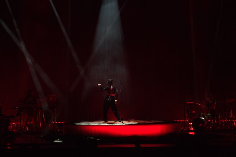 Photo of a woman striking a pose on a red stage under a spotlight