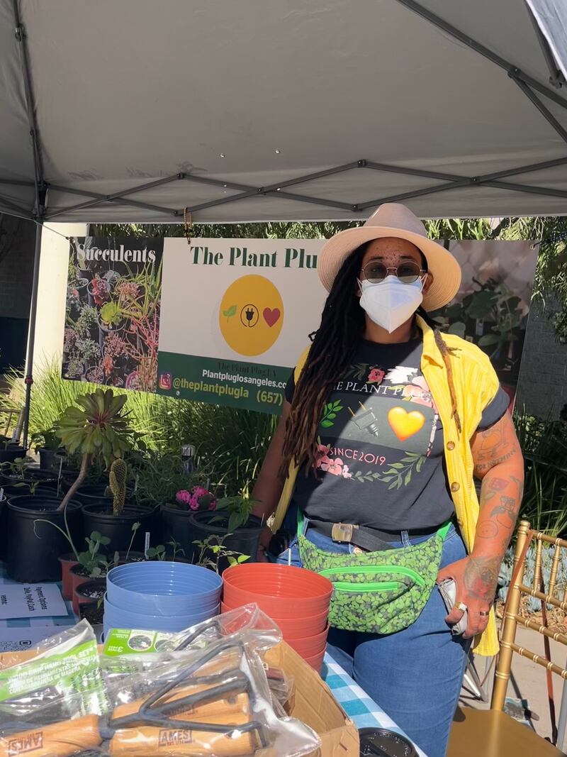 Plant Plug owner, Taylor Lindsey, poses in front of plant booth at farmers market.