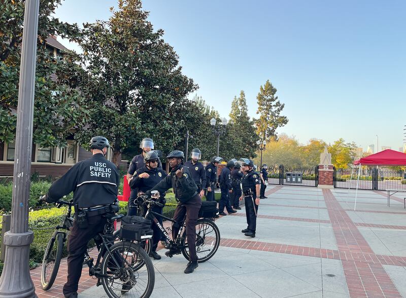 DPS officers on bicycles stand positioned outside the Trousdale Pkwy campus gates.