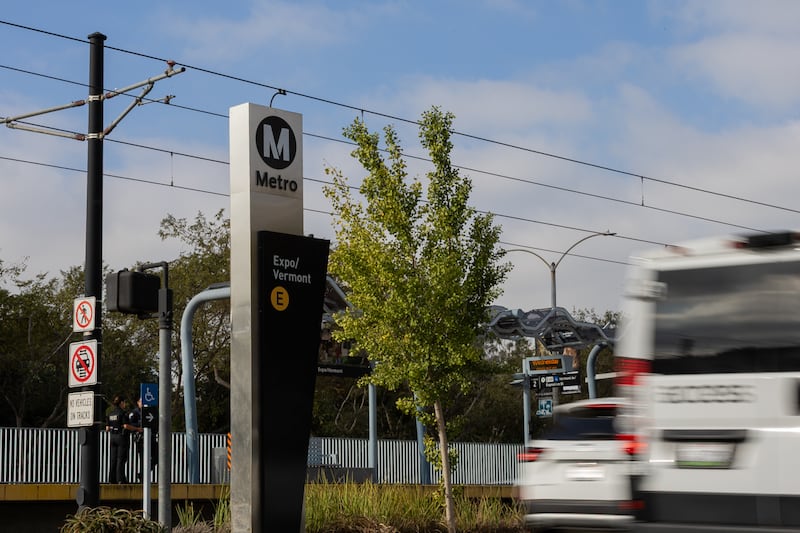 Cars fly past a rail station.
