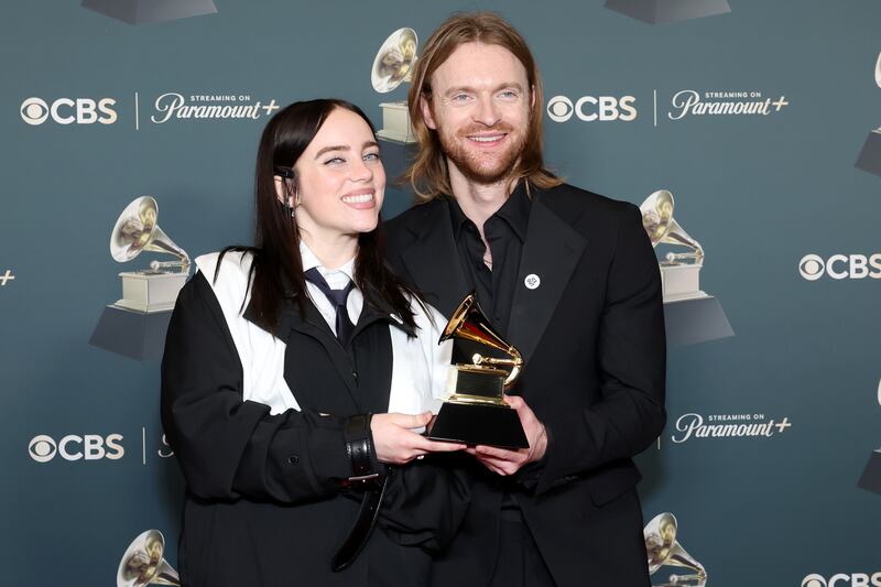 Billie Eilish and Finneas pose with their Grammy for Song of the Year while wearing pins that read "ICE OUT."