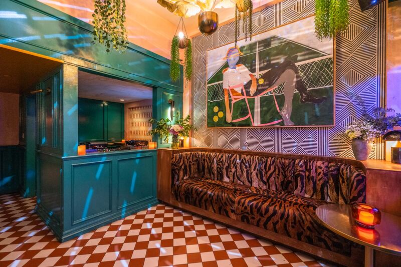 The inside of Honey's at Star Love, including a couch, a colorful painting, plants and disco lights.