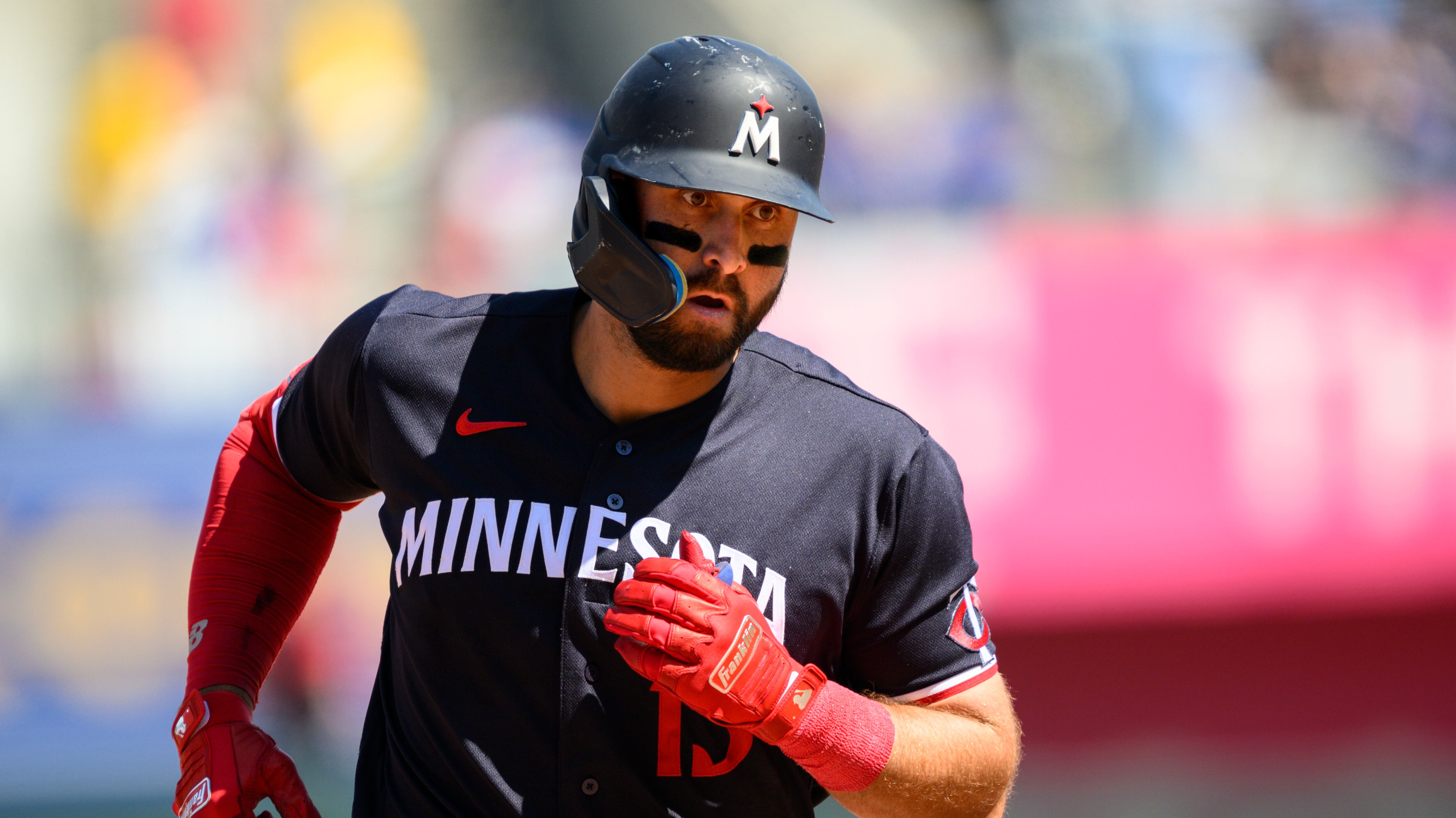 Joey Gallo is running during a baseball game. He is wearing a blue helmet with a blue jersey and a red sleeve on his right arm.