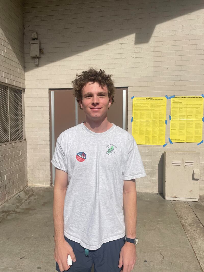 A man in a grey t-shirt standing in front of a building.