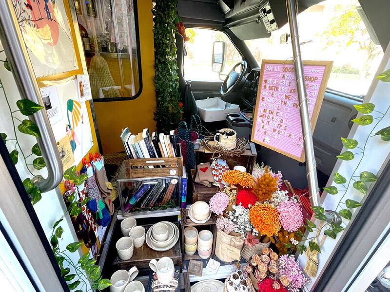 A photo of the flowers, pottery, books and other colorful gifts available at the mobile shop. There are vines and other florals in the background.