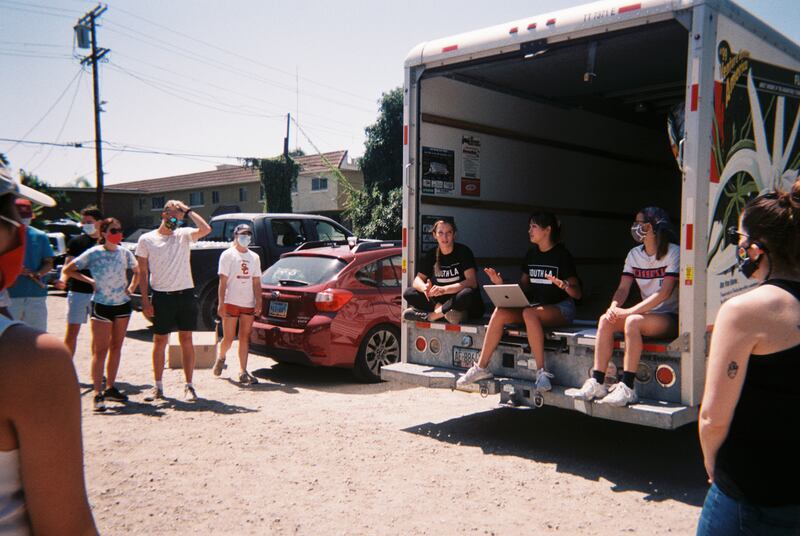 Catie Cummings and Aria Catano sitting on the edge of the U-Haul and briefing volunteers.