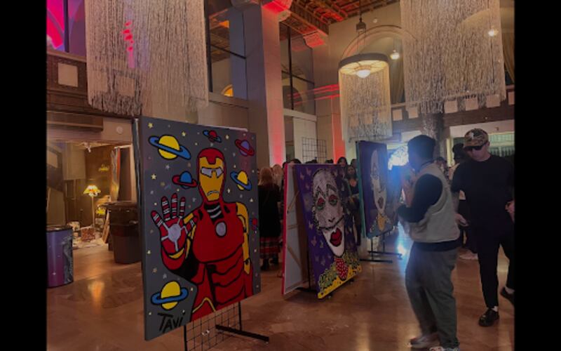 Attendees view a painting of Ironman in space in a showroom.